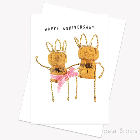 Champagne Girl - Happy Anniversary Card from the Love Letters collection by petal & pins. Card with two cork characters with the greeting 'Happy Anniversary', on a white background.